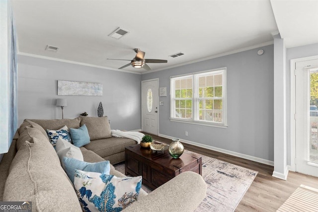 living room featuring light hardwood / wood-style floors, a wealth of natural light, crown molding, and ceiling fan