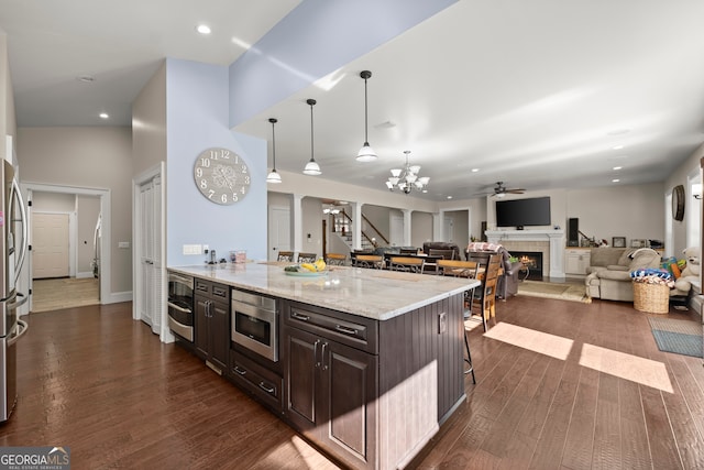 kitchen featuring appliances with stainless steel finishes, dark brown cabinetry, dark hardwood / wood-style floors, and a breakfast bar area