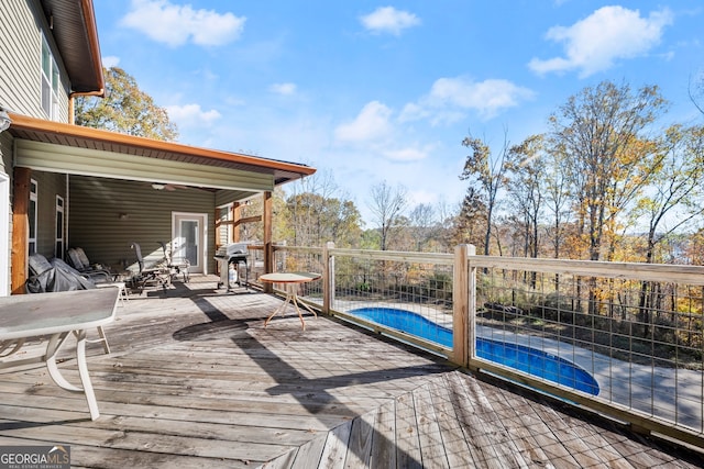 wooden deck with a fenced in pool and a grill