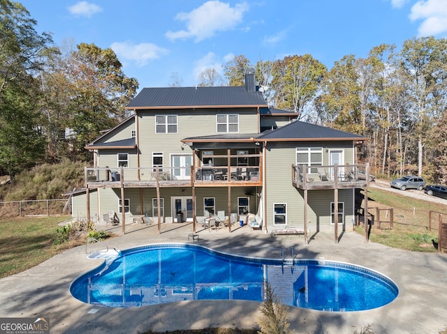 back of house with a pool side deck, a patio area, and a balcony