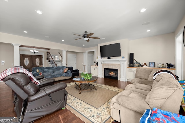 living room featuring ceiling fan with notable chandelier, hardwood / wood-style flooring, and a tiled fireplace