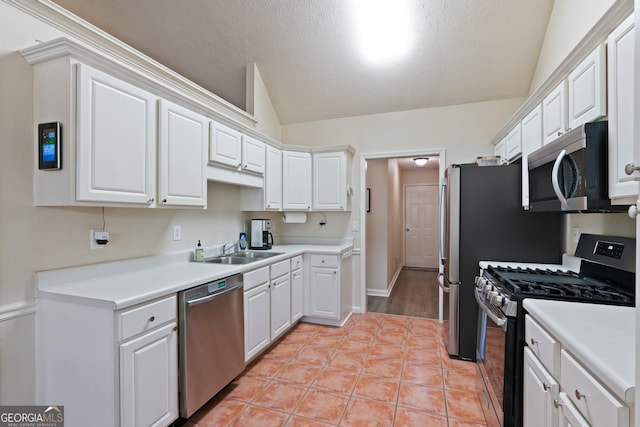 kitchen with lofted ceiling, white cabinets, sink, a textured ceiling, and stainless steel appliances