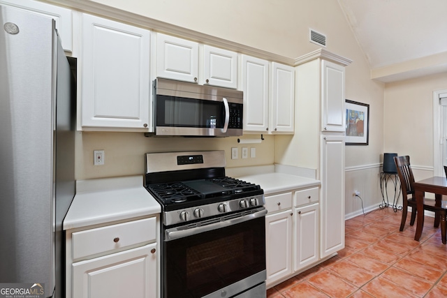 kitchen with light tile patterned floors, white cabinets, stainless steel appliances, and lofted ceiling