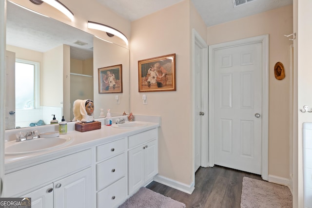 bathroom featuring vanity, a textured ceiling, hardwood / wood-style flooring, and walk in shower