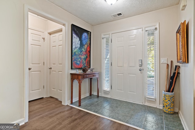 entrance foyer featuring a textured ceiling, dark hardwood / wood-style flooring, and a wealth of natural light