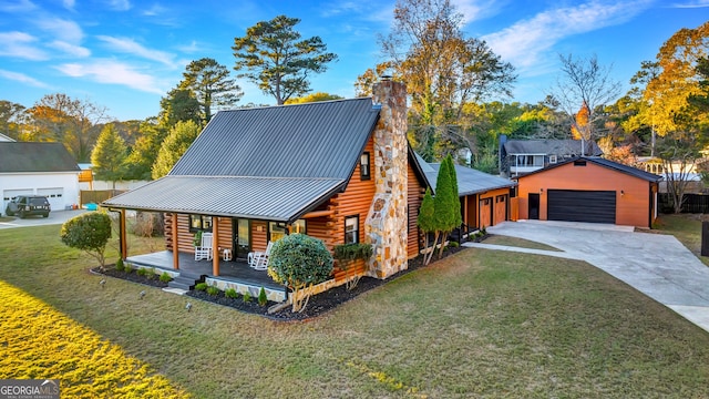 view of front of property featuring covered porch, an outbuilding, a garage, and a front lawn