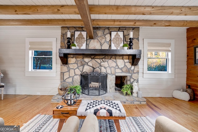 living room featuring a fireplace, beamed ceiling, and wood walls