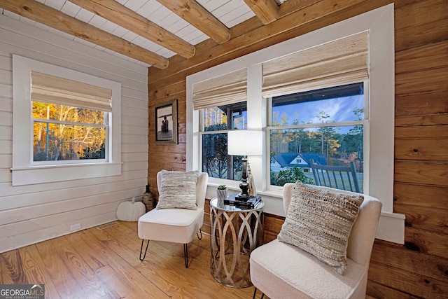 living area featuring beam ceiling, wood walls, hardwood / wood-style floors, and wooden ceiling