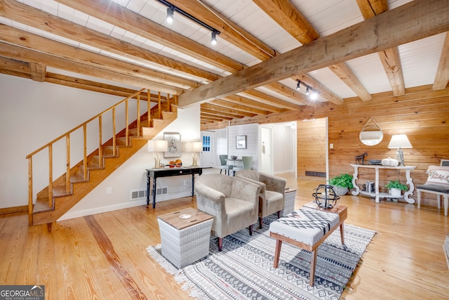 living room featuring wood walls, rail lighting, light hardwood / wood-style flooring, beam ceiling, and wood ceiling