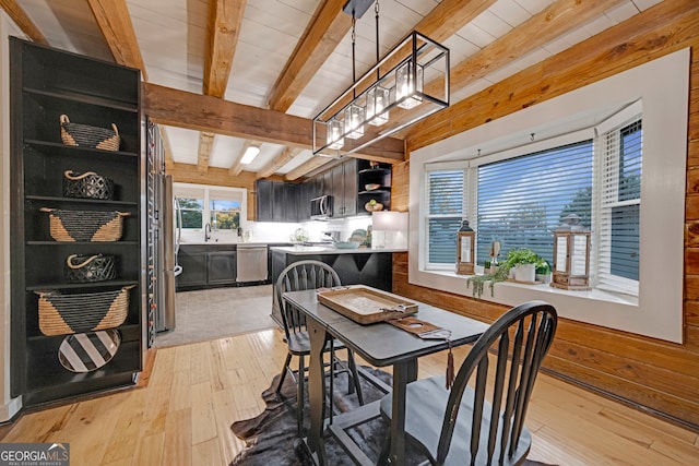 dining area with wooden ceiling, sink, wooden walls, light hardwood / wood-style flooring, and beam ceiling