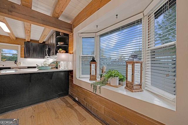 kitchen featuring beam ceiling, light hardwood / wood-style flooring, wooden walls, and wood ceiling