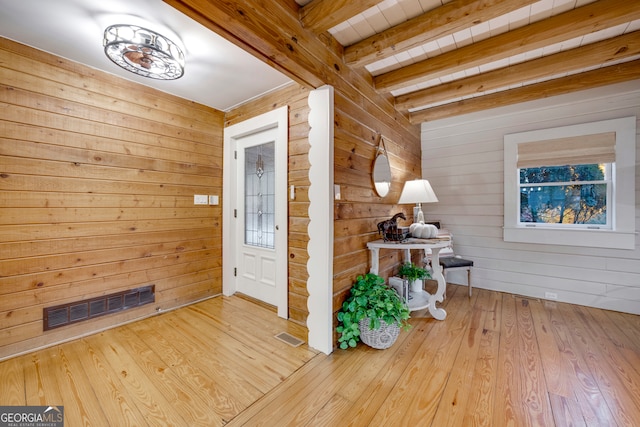 entrance foyer featuring beamed ceiling, light hardwood / wood-style floors, and wooden walls