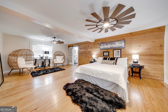 bedroom featuring beam ceiling, ceiling fan, light hardwood / wood-style flooring, and wood walls