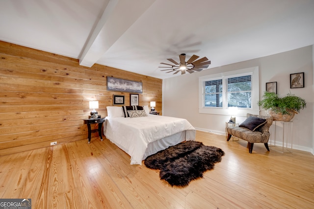 bedroom featuring beamed ceiling, hardwood / wood-style flooring, ceiling fan, and wood walls