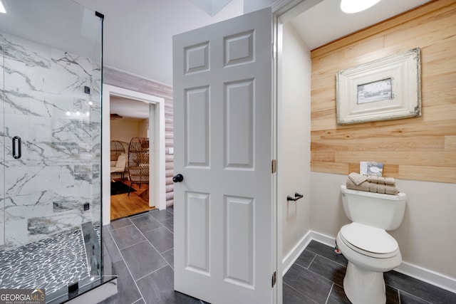 bathroom with wood walls, a shower with shower door, and toilet