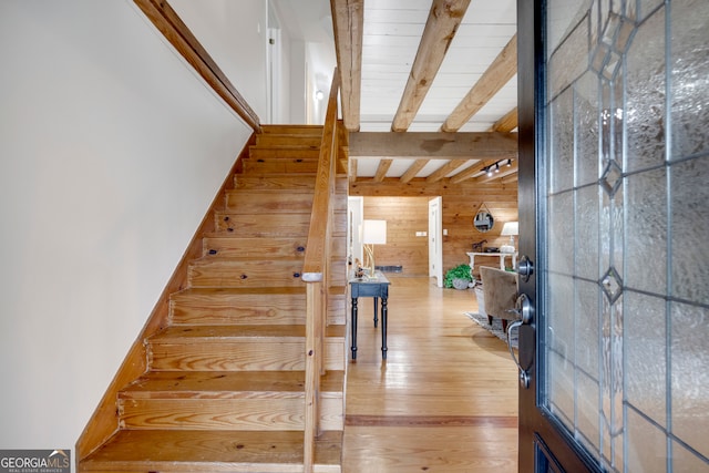 staircase featuring beam ceiling, hardwood / wood-style flooring, and wooden walls