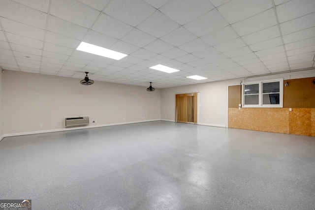 basement with a wall mounted AC and a drop ceiling