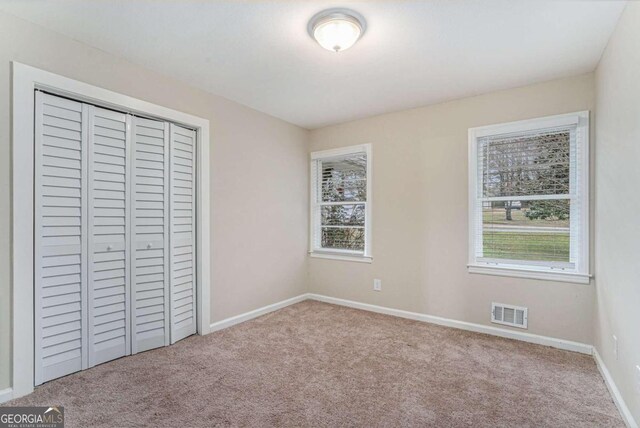 unfurnished bedroom featuring light carpet and a closet