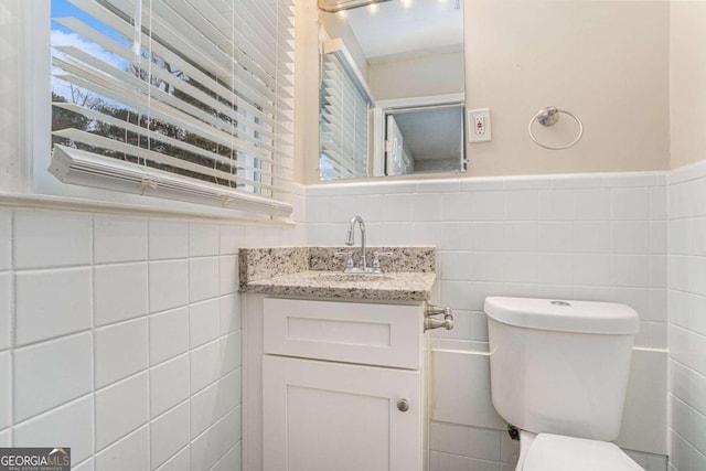 bathroom with vanity, toilet, and tile walls