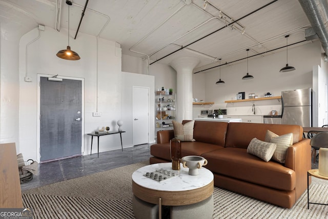 living room with a towering ceiling, concrete floors, and sink