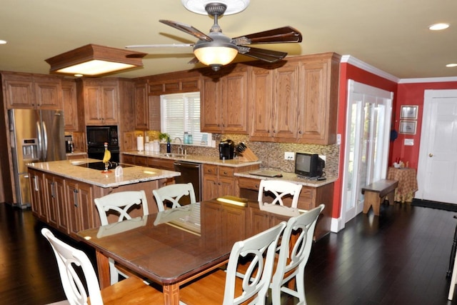 kitchen with tasteful backsplash, sink, black appliances, hardwood / wood-style flooring, and a center island