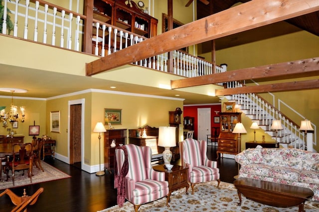 living room with a towering ceiling, ornamental molding, dark hardwood / wood-style floors, and a notable chandelier