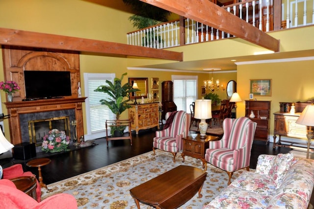 living room featuring hardwood / wood-style flooring, beam ceiling, a towering ceiling, and a tile fireplace