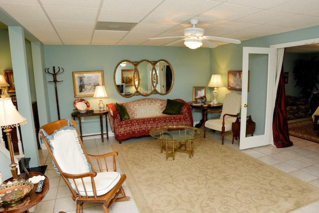 living area featuring light tile patterned floors, a paneled ceiling, and ceiling fan