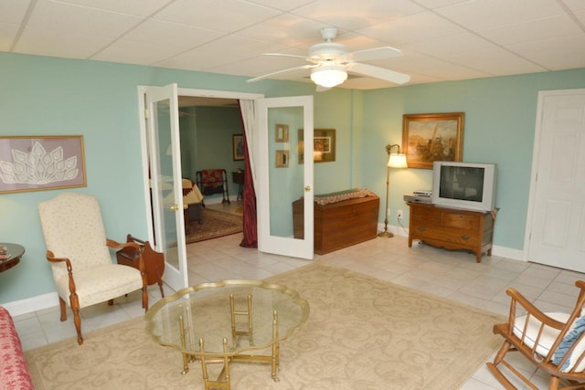 living area with tile patterned floors, a drop ceiling, ceiling fan, and french doors