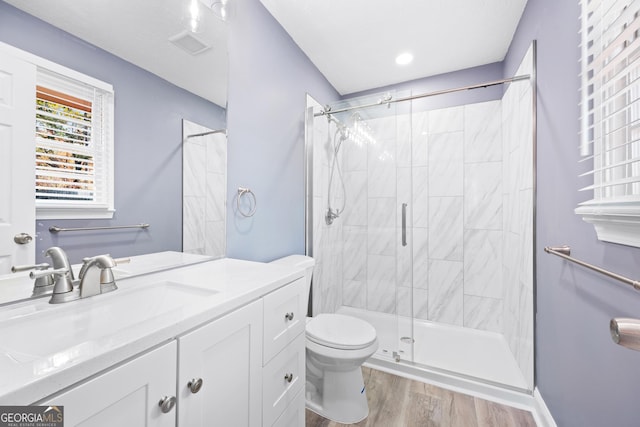 bathroom featuring hardwood / wood-style flooring, vanity, toilet, and a shower with door