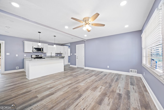 kitchen with ceiling fan, stainless steel appliances, decorative light fixtures, white cabinets, and light wood-type flooring