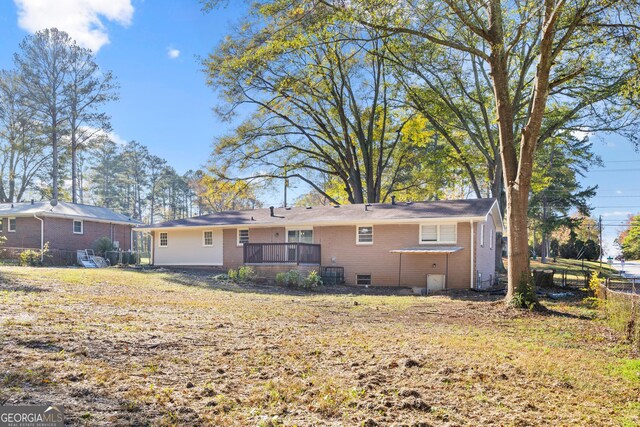 back of property with cooling unit, a deck, and a yard