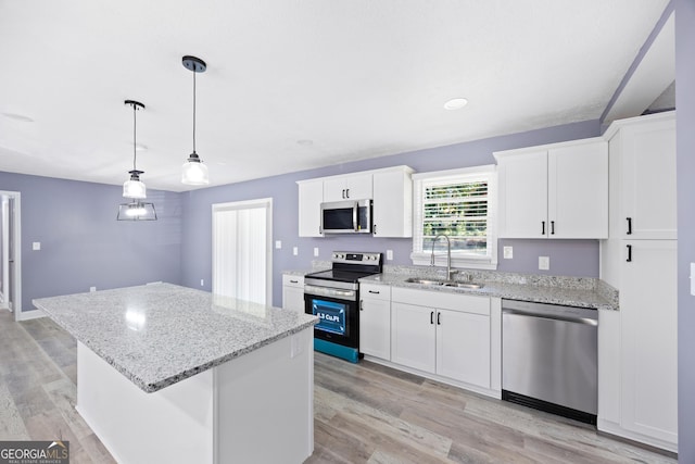 kitchen with stainless steel appliances, sink, pendant lighting, white cabinets, and a kitchen island