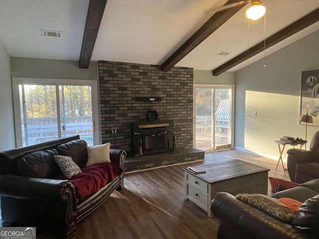 living room with a textured ceiling, ceiling fan, hardwood / wood-style floors, vaulted ceiling with beams, and a wood stove