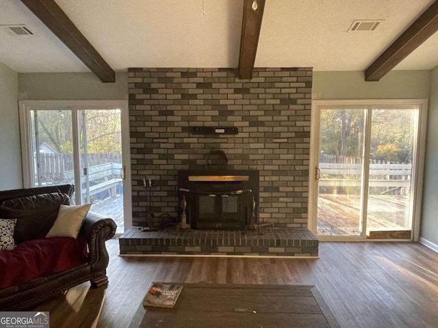 living room featuring beamed ceiling, dark hardwood / wood-style floors, and a wood stove