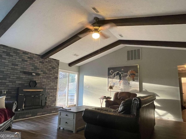 living room with vaulted ceiling with beams, a wood stove, ceiling fan, and dark wood-type flooring