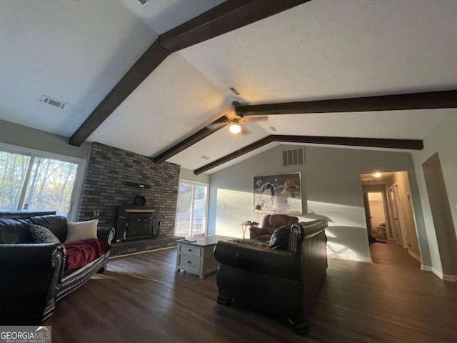 living room with vaulted ceiling with beams, a wood stove, ceiling fan, and dark wood-type flooring