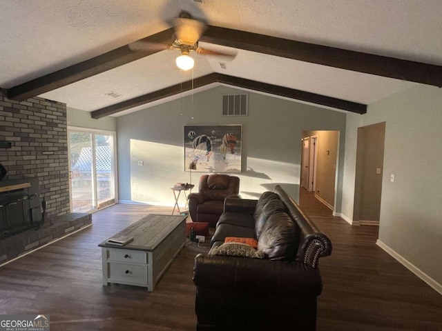 living room with a textured ceiling, ceiling fan, dark wood-type flooring, vaulted ceiling with beams, and a wood stove