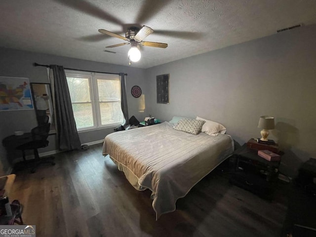 bedroom featuring ceiling fan, dark hardwood / wood-style floors, and a textured ceiling