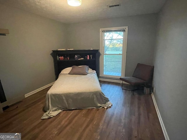 bedroom featuring dark hardwood / wood-style flooring and a textured ceiling