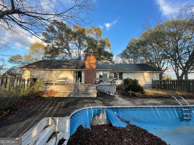 rear view of property featuring a pool side deck