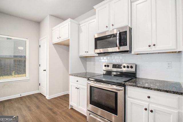 kitchen featuring appliances with stainless steel finishes, tasteful backsplash, dark stone counters, dark hardwood / wood-style floors, and white cabinetry