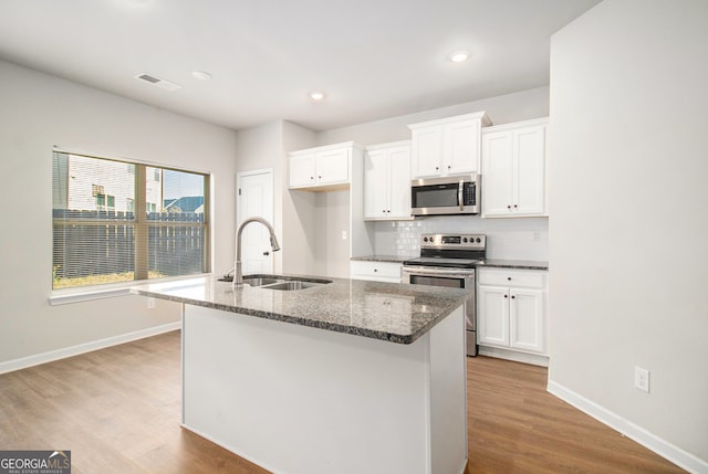 kitchen with a center island with sink, light hardwood / wood-style floors, sink, and appliances with stainless steel finishes