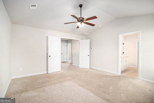 unfurnished bedroom featuring light carpet, ensuite bath, vaulted ceiling, and ceiling fan