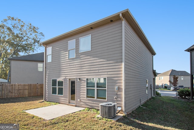 rear view of property featuring a yard, a patio, and central AC