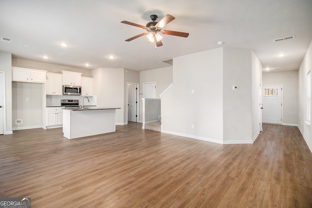 unfurnished living room featuring dark hardwood / wood-style floors, ceiling fan, and sink