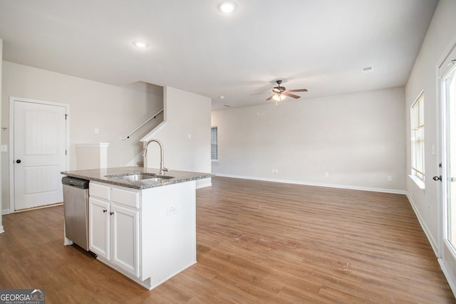 kitchen featuring sink, light hardwood / wood-style flooring, stainless steel dishwasher, an island with sink, and white cabinets