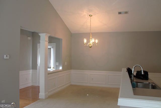 unfurnished dining area with decorative columns, light carpet, sink, an inviting chandelier, and vaulted ceiling