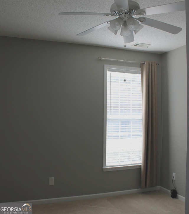 empty room with ceiling fan, a textured ceiling, and light carpet