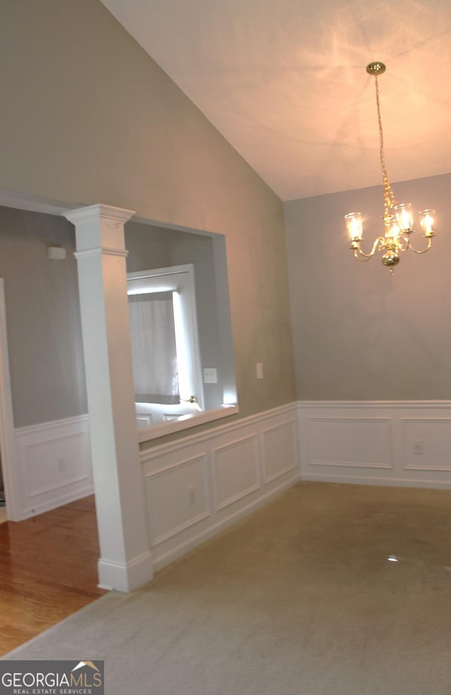 unfurnished dining area with decorative columns, vaulted ceiling, a chandelier, and carpet floors